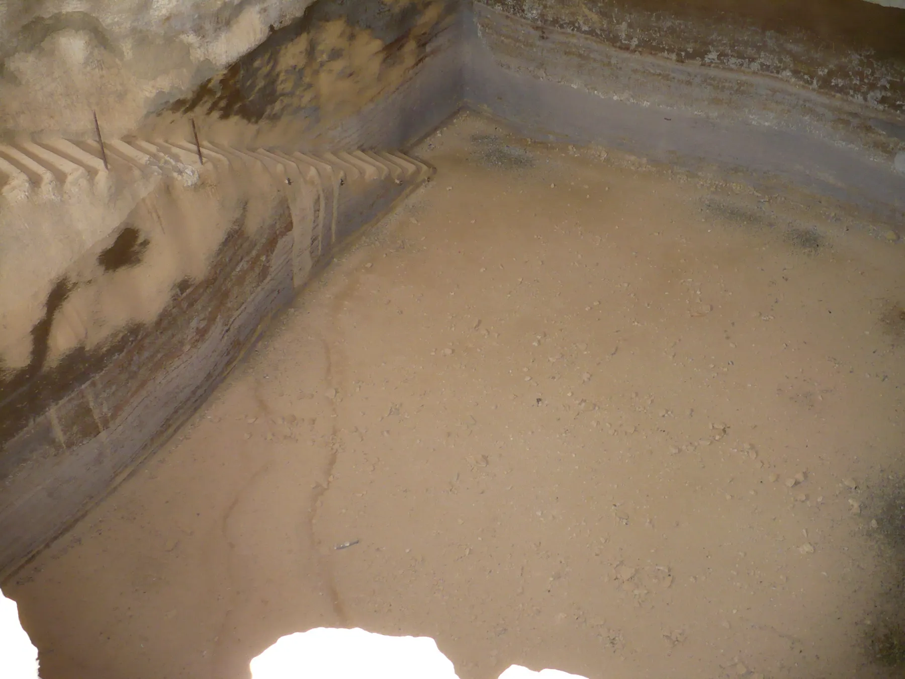 The plastered interior of a rock-cut water cistern at Masada, with a flight of cut steps descending along the left-hand wall