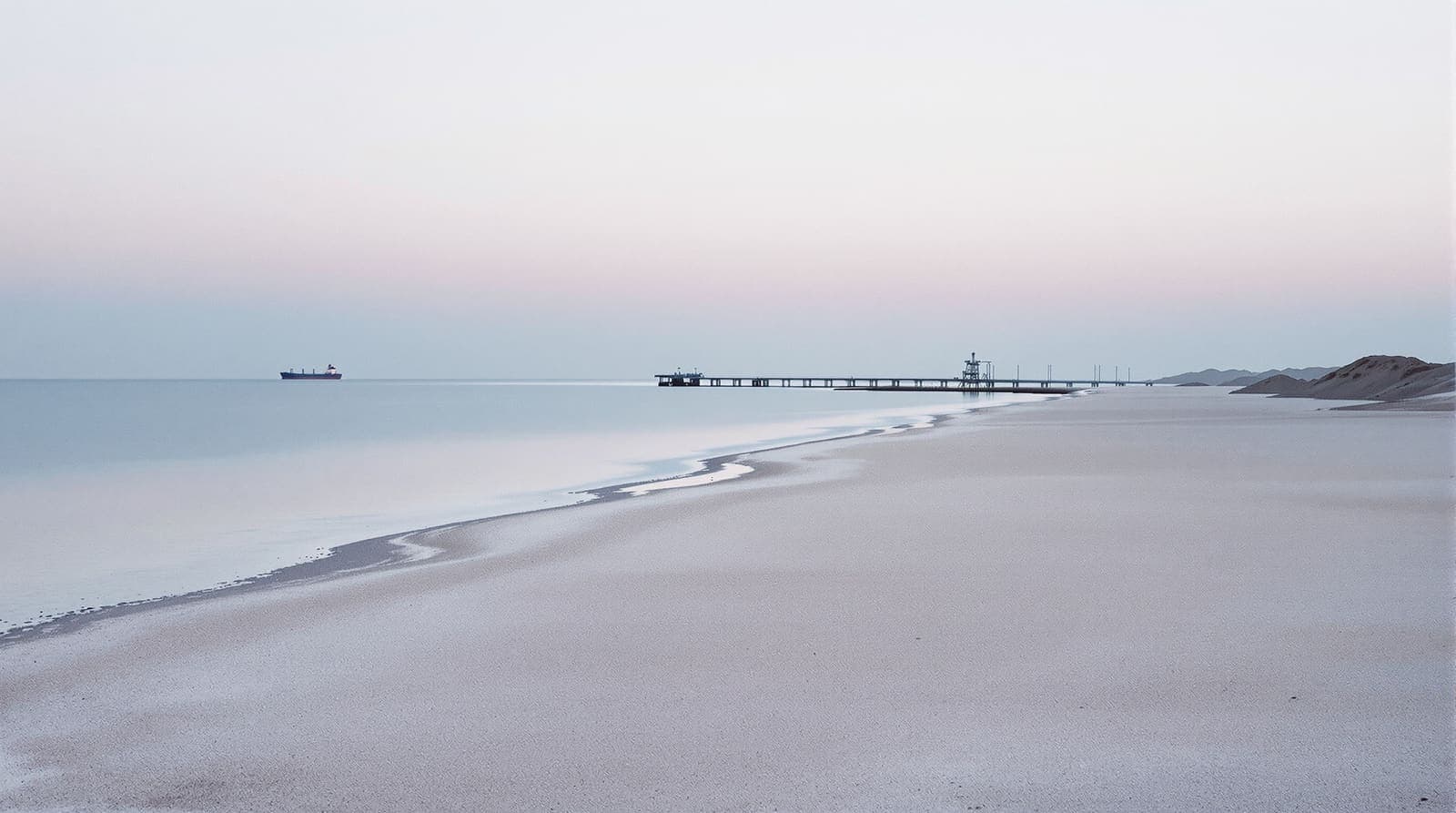 Illustration of an arid southern coastline at dawn with calm water, hazy ridges and distant harbour structures far across the bay.
