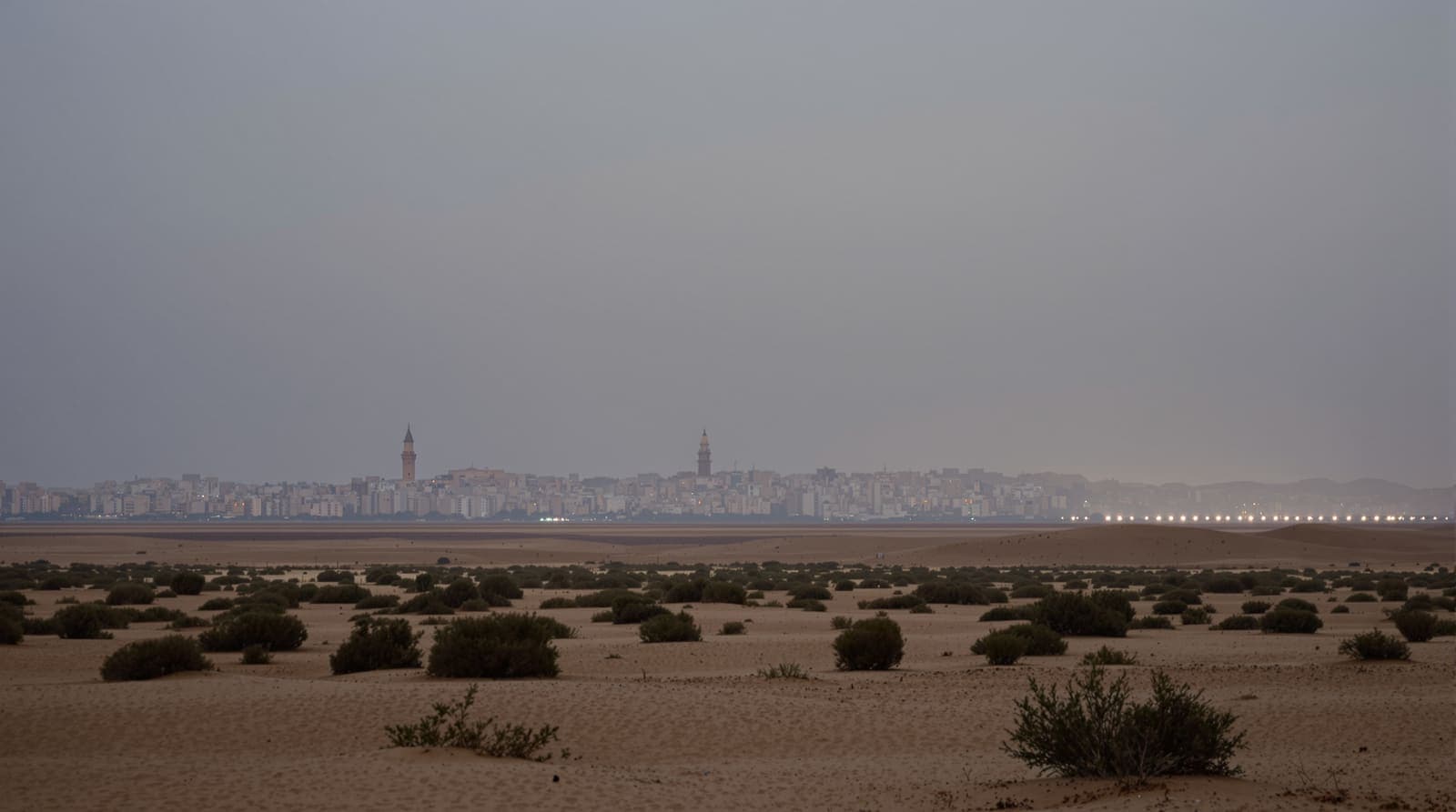 Illustration of a hazed southern Gaza skyline seen from distant scrub hills at dawn under an overcast sky.