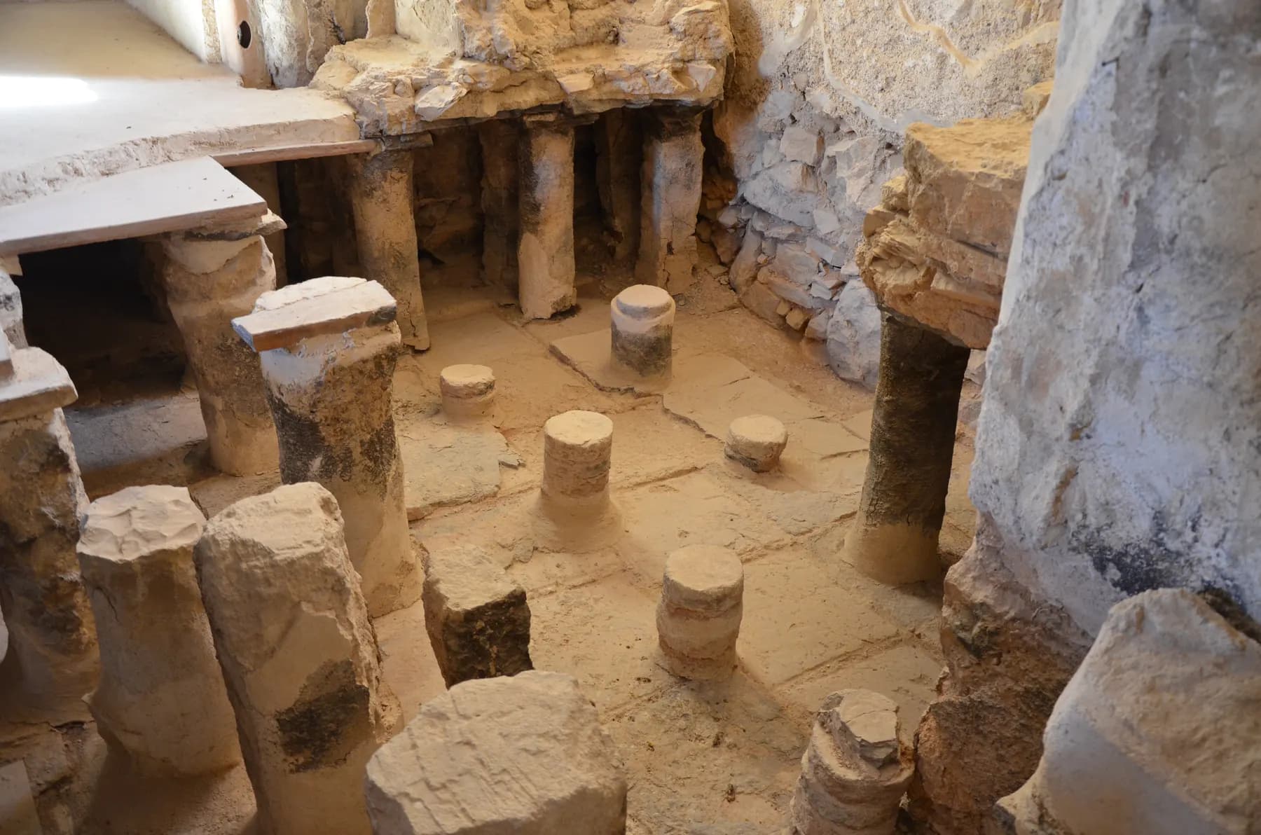 Rows of short stone pillars under the raised floor of the caldarium in Herod's large bathhouse at Masada, with slabs of the suspended floor still in place at one side