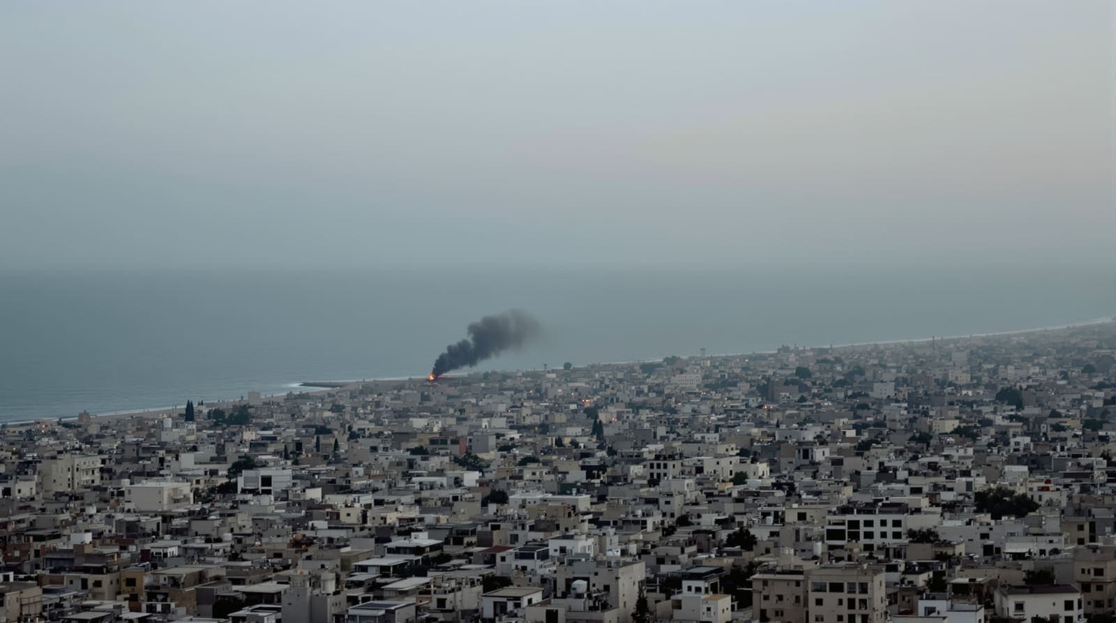 Illustration of an aerial view of a dense Gaza cityscape at dusk with a distant column of smoke near the coast.
